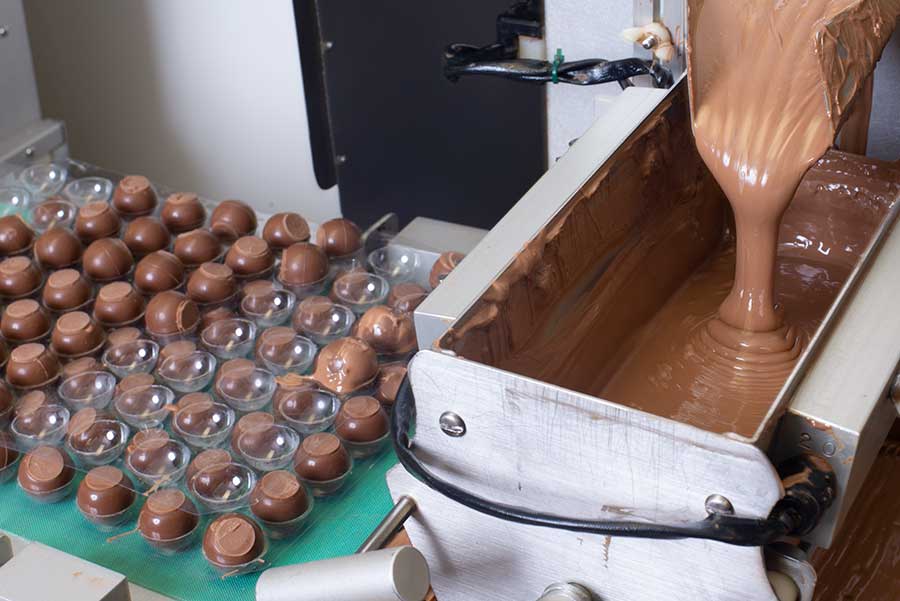 Vasilow's chocolate enrobing machine with liquid chocolate flowing